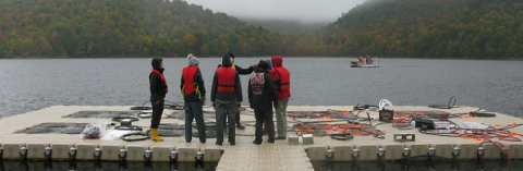 students in life vests standing on a platform in a lake