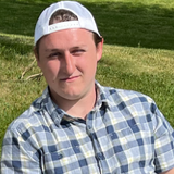 Guy with checkered shirt and white cap soaking in the sun