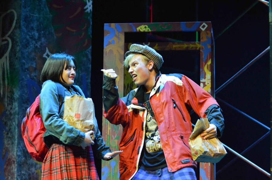 A young man and women dressed in colourful clothes on a colourful urban background are talking energetically.