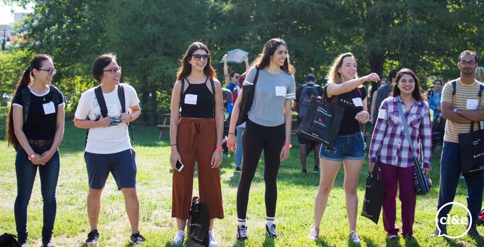 students stand in line outside with happy faces, participating in an orientation activity