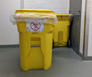 Yellow garbage container with a plastic bag and a crossed out biohazard symbol