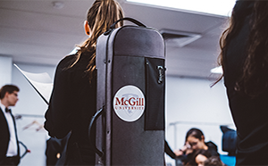 Musician carrying instrument case with schulich school of music logo