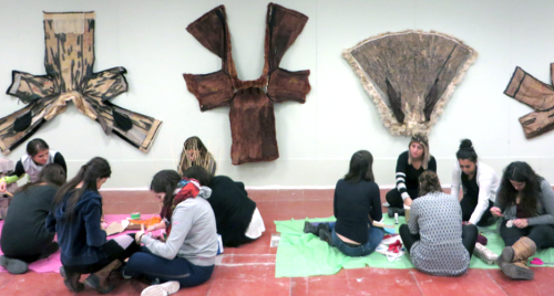 students sitting on the floor in front of furs displayed on wall