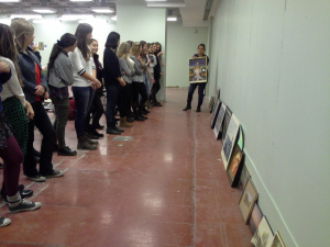 students looking at pictures lined up against a wall