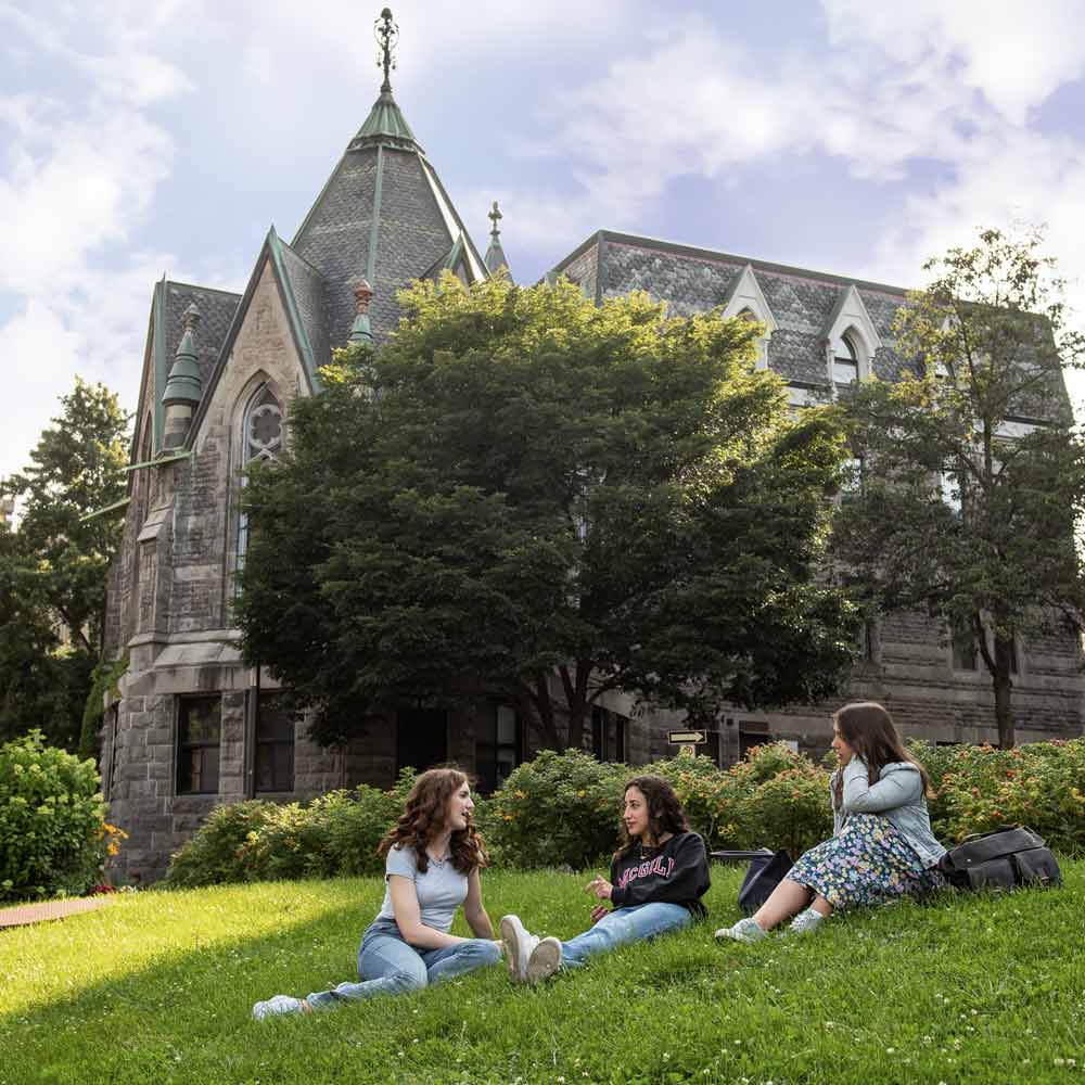 A group of students sitting on grass in front of a building